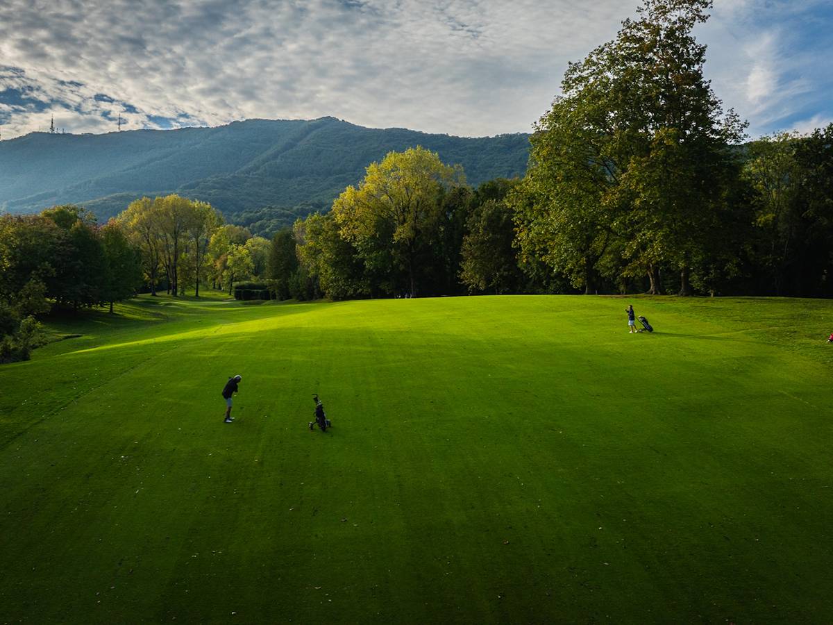 Two golfers on a wide fairway at Real Golf Club de San Sebastián in Hondarribia - the Basque mountains rising behind, at José María Olazábal's home course